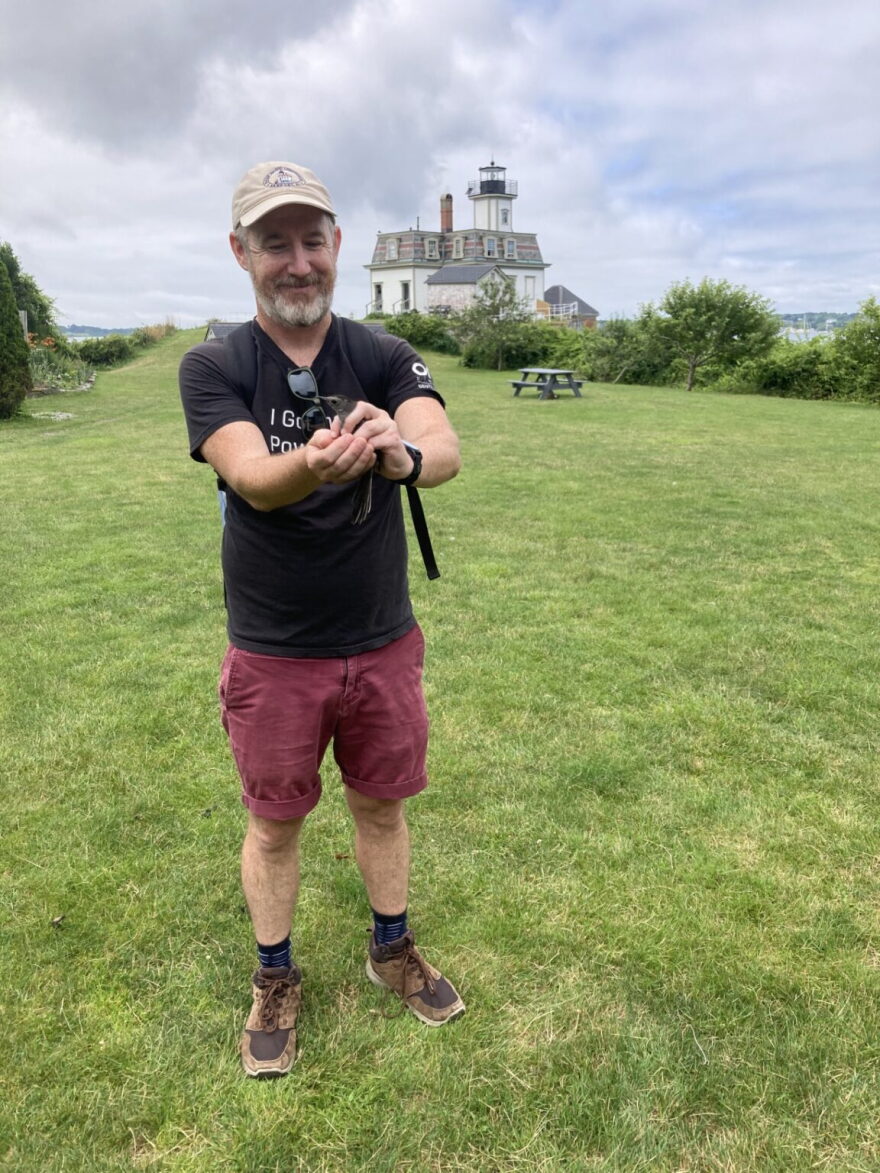 Sean O’Connor on Rose Island, holding a bird as part of a multiyear study of Rose Island birds led by Salve Regina University professor Dr. Jameson Chace.
