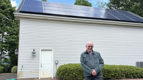 Retired Navy doctor Doug McNeill in front of solar panels on his home garage in Chesapeake on Thursday, May 8, 2025.