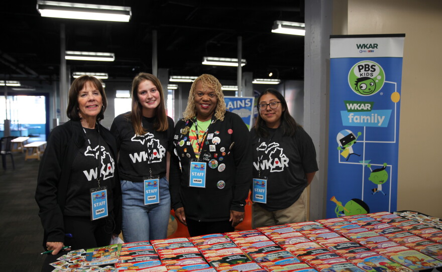Robin Pizzo and other WKAR team members hand out free books to visiting families at Be My Neighbor Day with WKAR.