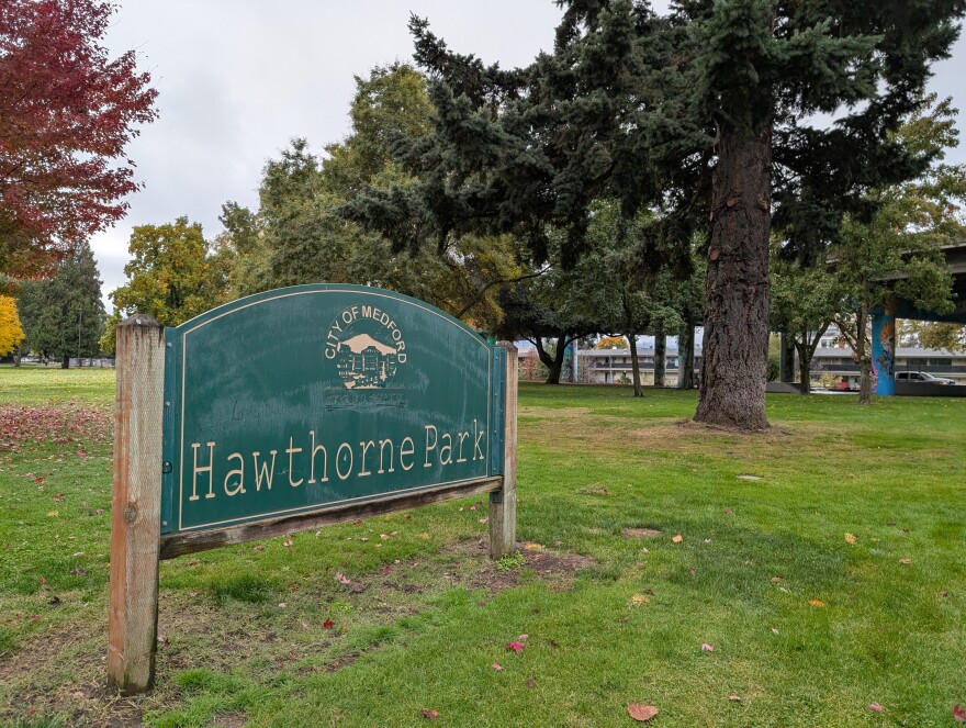 A grassy park with some trees. A sign in the foreground reads, "City of Medford, Hawthorne Park."