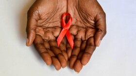 Two hands hold a red ribbon signifying World AIDS Day