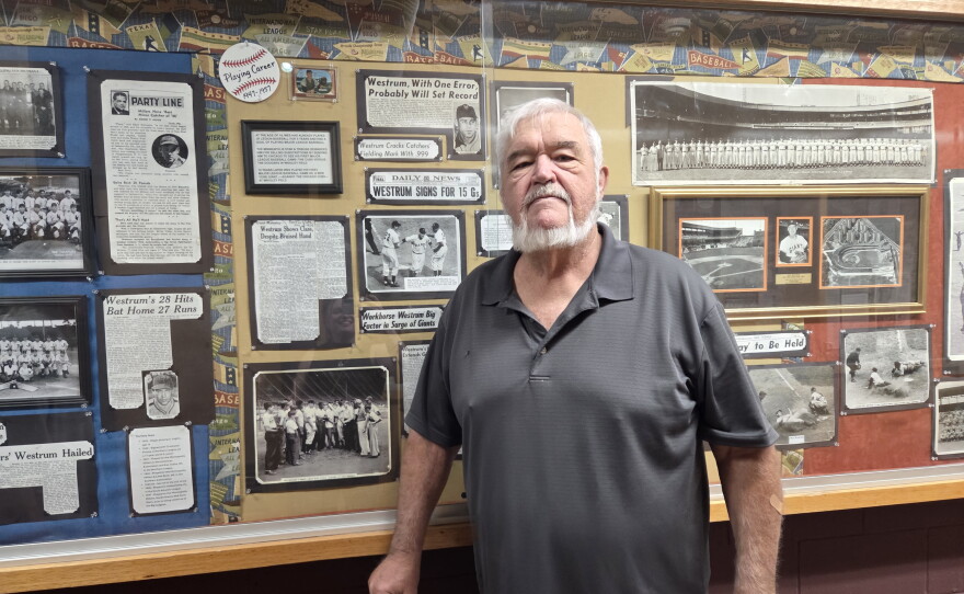 Robert Westrum of Clearbrook poses in front of a display of his cousin Wes Westrum of Clearbrook, who played in the majors as a New York Giant and later coached the New York Mets. Westrum was casting his vote on Primary Election Day, Aug. 11, 2026, at Clearbrook City Hall.