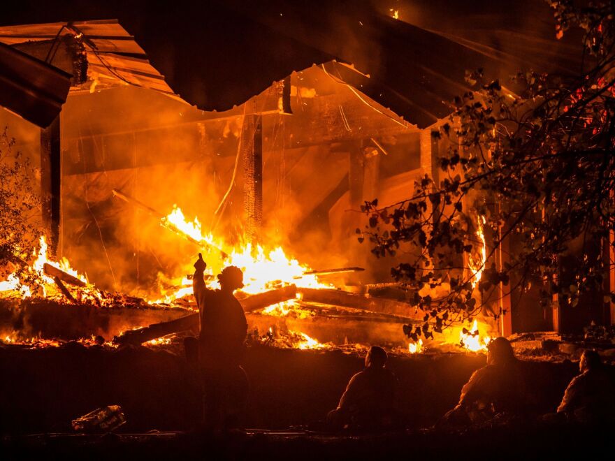 Firefighters look on as a structure burns during the Kincade Fire off Highway 128, east of Healdsburg, Calif., on Tuesday.