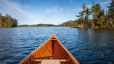 Wooden canoe on a blue Boundary Waters lake with islands on an autumn morning