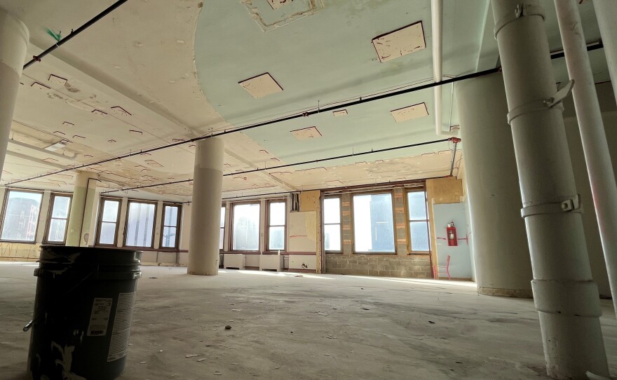 A room is empty except for a buck and a small pink chair near the wall-mounted fire extinguisher in the distance. This is the future space of Haley & Aldrich environmental engineering and consulting that has sat empty for eight years or more on the southeast corner of Sibley Square.