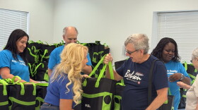 A female Duke Energy employee hands a senior a green bag