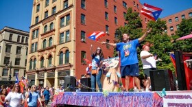 Float riders at Springfield's 2019 Puerto Rican parade waving Puerto Rican flags behind marchers. 