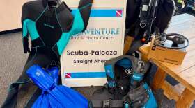 Scuba gear draped over a sandwich boarding reading "Scuba-palooza Straight Ahead"
