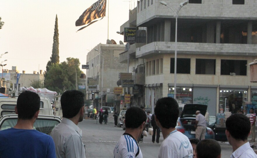 Men look at a jihadist flag flying over Raqqa on Sept. 28, 2013.