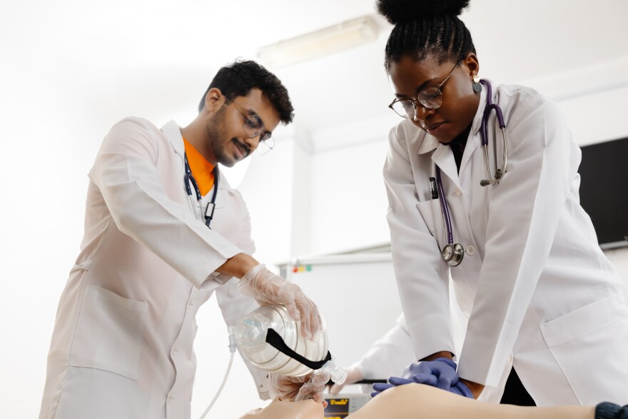 A couple of medical professionals are carefully performing a procedure on a patient in a hospital setting.