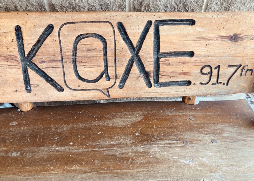 A wooden bench that says "KAXE 91.7fm" on it.