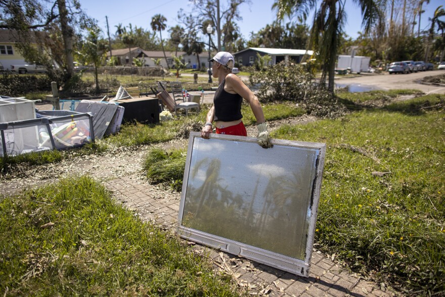 Lindsay Comstock removes ruined furniture from her home in the Dean Park historic district of Fort Myers, Fla. on Oct. 2, 2022, after Hurricane Ian passed through the area. Lindsay had evacuated with her family and had come back to her home to clean up and pick up the remains.