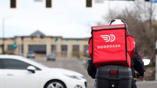 FILE - A food delivery motorcycle rider waits for the traffic light to change March 30, 2020, in Lone Tree, Colo. (AP Photo/David Zalubowski, File)