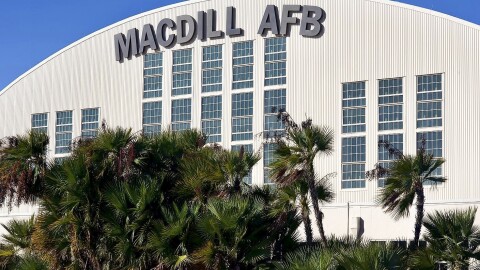 Airport hangar with the words MacDill AFB at the top. Palm trees are in front of the building. 