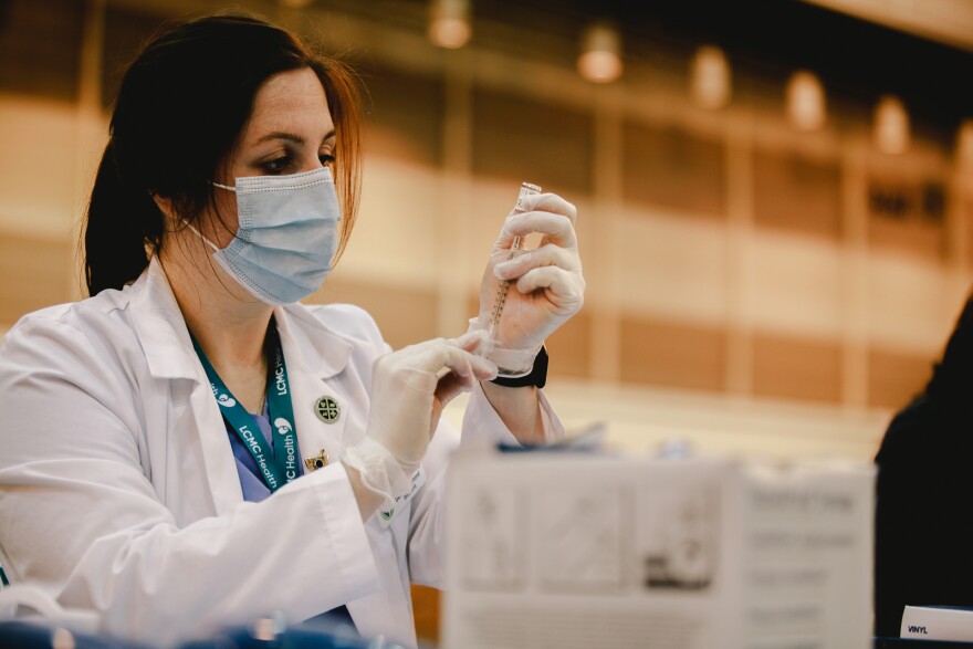 A healthcare professional administers a dose of a COVID-19 vaccine at the Ernest N. Morial Convention Center in New Orleans.