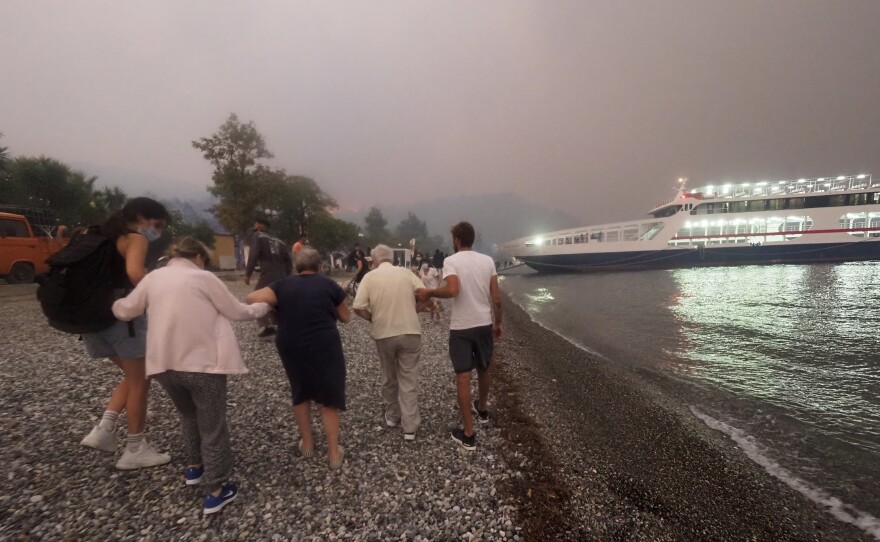 People embark a ferry during an evacuation from Kochyli beach as wildfire approaches near Limni village on the island of Evia on Friday.