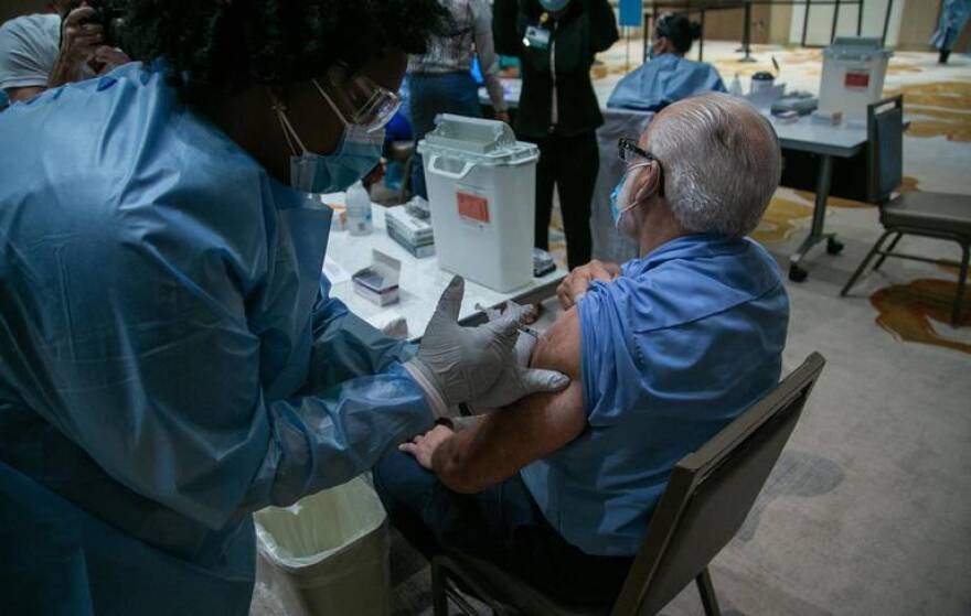 A nurse vaccinates environmetal services worker Gustavo Lazo early Wednesday morning as Baptist Health began administering the first COVID-19 vaccines for its front-line healthcare workers in Miami, Florida, on Dec. 16, 2020.