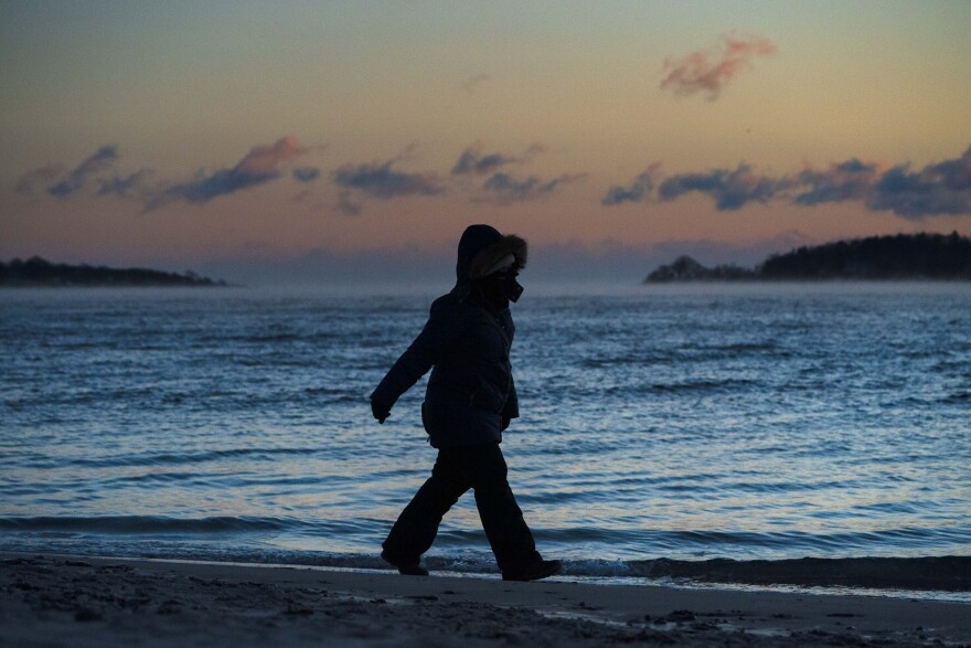 A beach walker is bundled for the cold in single digit temperatures Fahrenheit, Tuesday, Jan. 11, 2022, in South Portland, Maine.