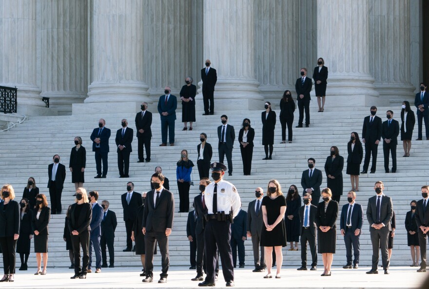 Former law clerks for Justice Ruth Bader Ginsburg stand on the steps of the U.S. Supreme Court in Washington, D.C., as they await the arrival of the casket on Wednesday.