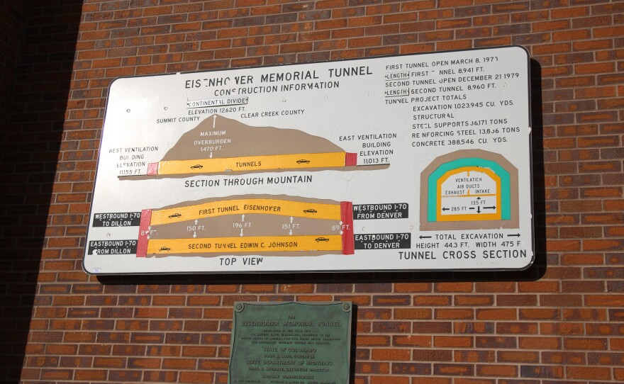 An informational graphic on a metal sign on a brick wall shows how the tunnels were built in the mountain.