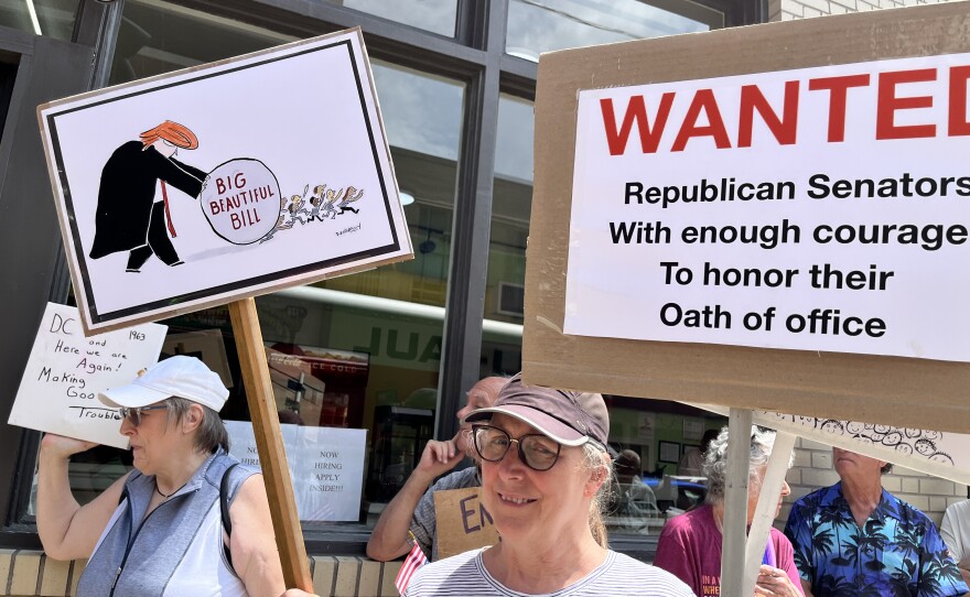 A passionate protestors in Scranton holds up two signs during a press conference about the implications of the One Big Beautiful Bill in Northeast Pennsylvania.