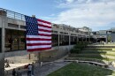 People gaze down at the site where Charlie Kirk was shot, above which hangs an American flag, at Utah Valley University, Monday, Sept. 15, 2025, in Orem, Utah.