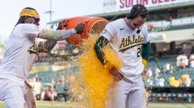 A baseball player dumps a cooler of liquid over another player