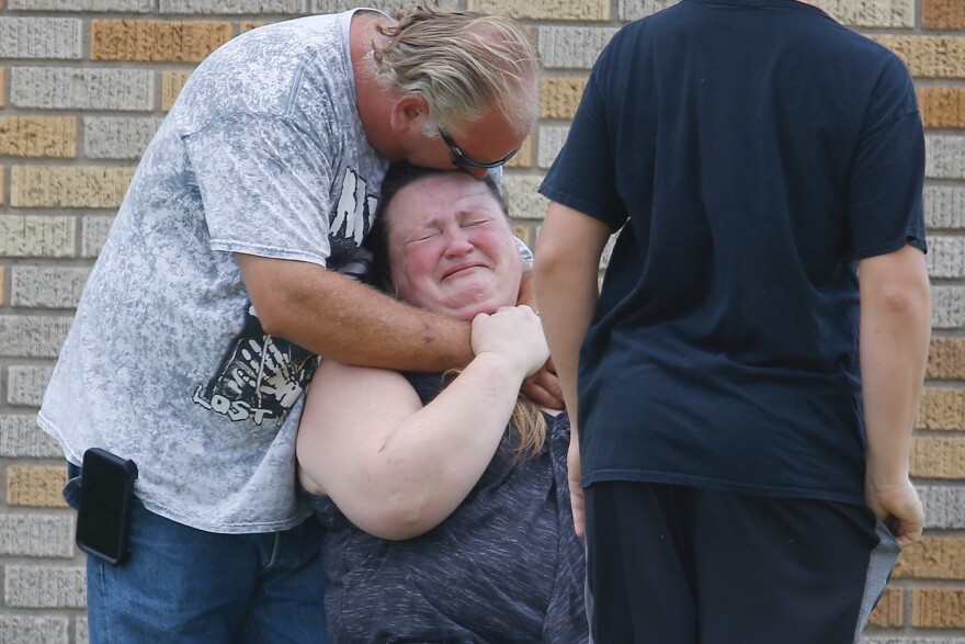 A man hugs a woman outside the Alamo Gym where parents wait to reunite with their kids following a shooting at Santa Fe High School.