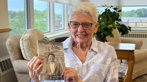 Woman holds up book. 