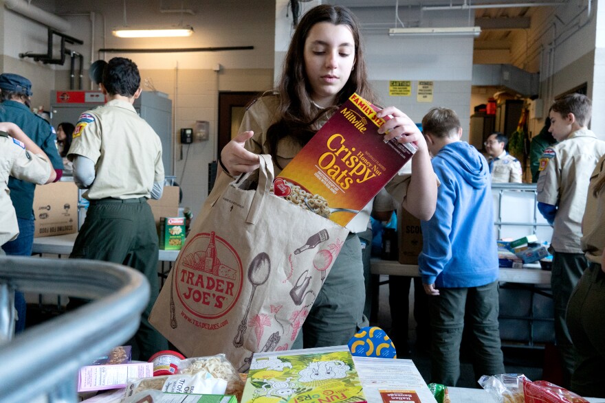 A scout sorts a box of Crispy Oats cereal for the annual Scouting America food drive in Clayton, Mo.