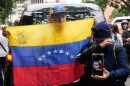 A man holds up a Venezuelan flag during the wake of Carmen Navas, the mother of Victor Hugo Quero, who authorities said died in custody following his arrest about a year earlier, in Caracas, Venezuela, Tuesday, May 19, 2026. (AP Photo/Ariana Cubillos)