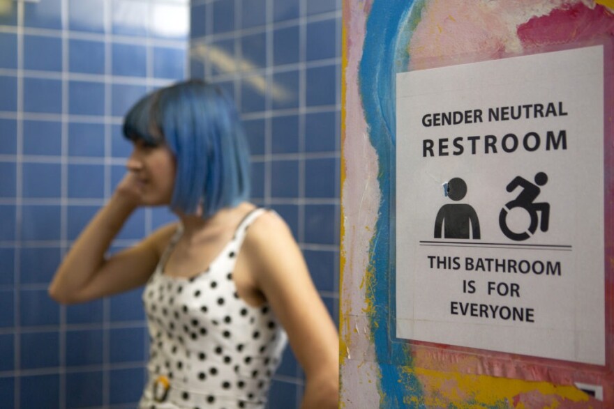 A nonbinary person next to gender-neutral sign to a bathroom. Photo by Zackary Drucker/Broadly’s Gender Spectrum Collection
