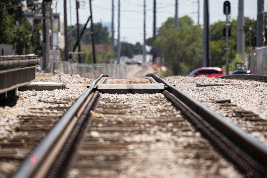 Railroad tracks near Kramer Station. The perspective is low, and you can see gravel around the tracks and a nearby crossing. 