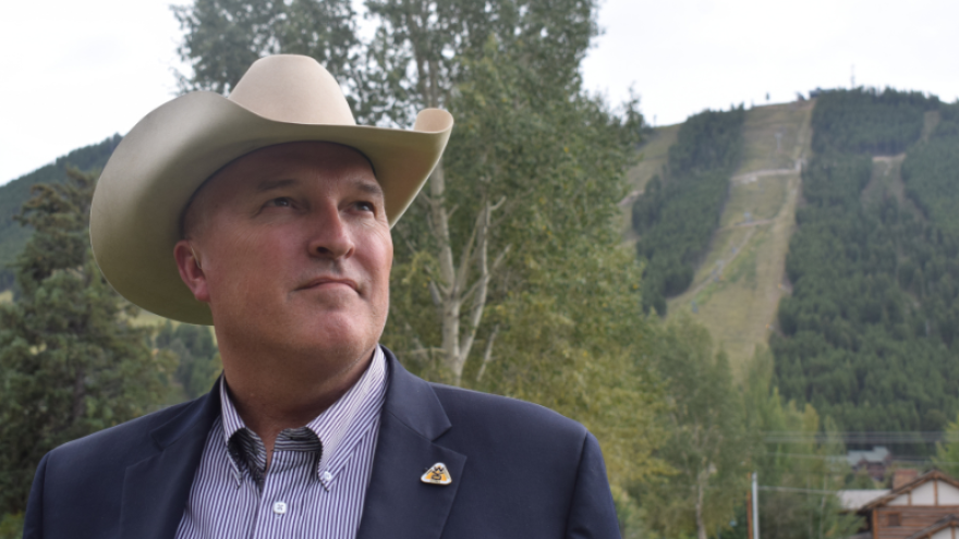A man in a cowboy hat looks off into the distance.