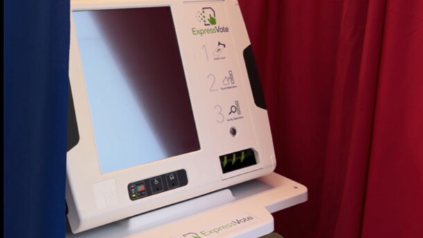 Electronic voting machine with a blank screen surrounded by a blue curtain on the left and a red curtain on the right. 