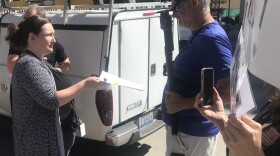 A library staffer presents Drew Ribar (right) with written notice of his temporary suspension on June 20, 2024.
