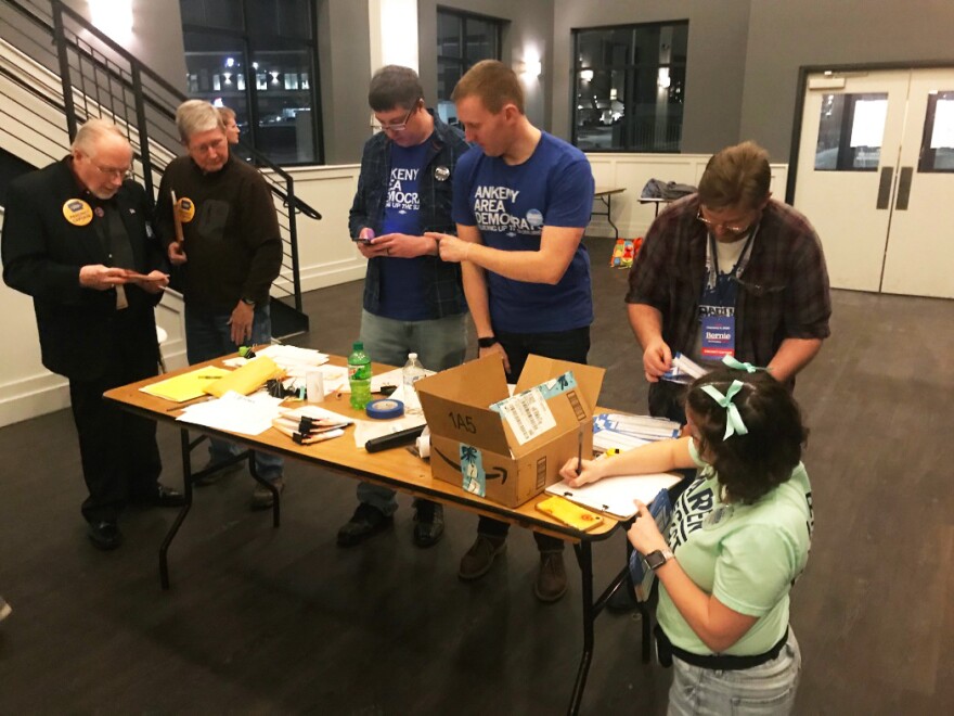 People stand around a table and look over papers.