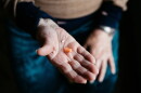 a person holds two pills, one orange and one while, in hands