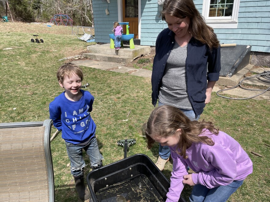 Mom Courtney Tyson looks on as her children dig through a wagon for frog eggs.
