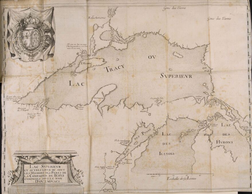 A 17th-century French engraved map depicting Lake Superior and the surrounding Great Lakes region. The map is printed on aged, yellowed paper with fold lines. Lake Superior is labeled "Lac Tracy ou Superieur" while Lake Huron appears as "Lac des Hurons," Lake Michigan as "Lac des Ilinois," and Green Bay as "Baye des Puans." Indigenous nations are labeled across the map and Jesuit mission locations are marked. A ornate frame in the lower left contains text that reads "Lac Superieur et autres lieux ou sont les Missions des Peres de la Compagnie de Iesus comprises sous le nom d'Outaovacs.” A coat of arms appears in the upper left corner. 
