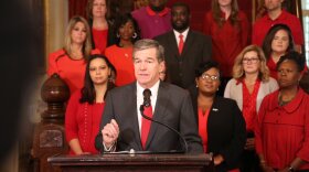 Flanked by educators dressed in red on November 8, Gov. Roy Cooper vetoed four bills that he said "prioritized more corporate tax cuts over a real teacher pay raise and urged legislators to come together and come up with a compromise"