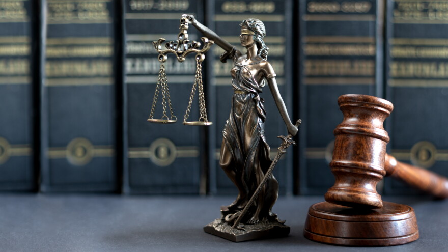 A justice statue rests on a desk next to a judge's gavel.