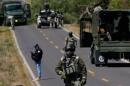 A road blockade is seen on a road in Mexico with military personnel and vehicles. 