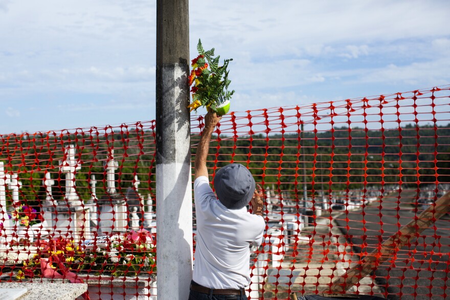 Francisco Rosado brought flowers for his mother's grave. But unable to reach it, he dropped them over the fence keeping him and other visitors away from damaged areas of the Lares Municipal Cemetery.