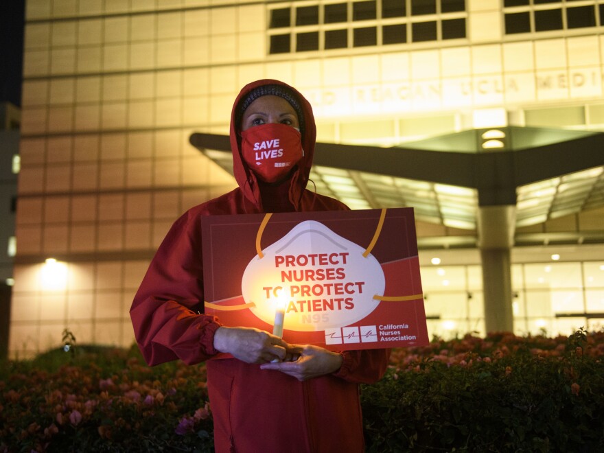 A nurse holds a candle during a vigil in Los Angeles last month for health care workers who have died from COVID-19. The vigil was organized by California Nurses United.