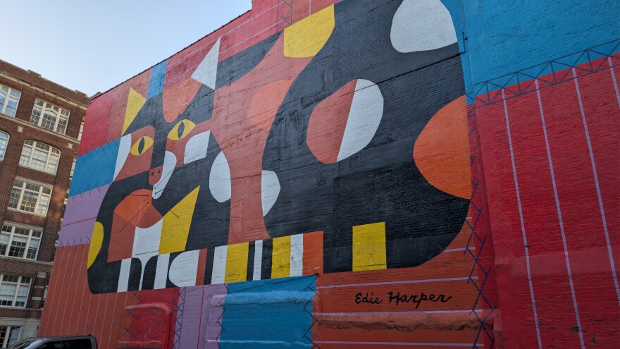 A stylized painting on a wall of a sitting cat.