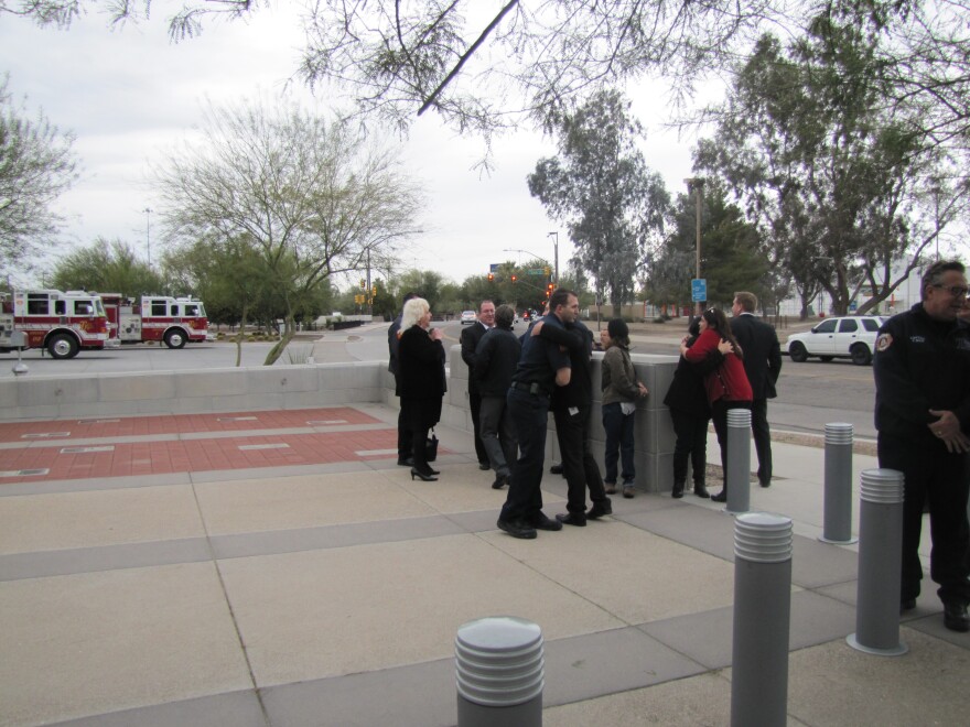 People hug after a bell-ringing ceremony at a fire station in downtown Tucson.