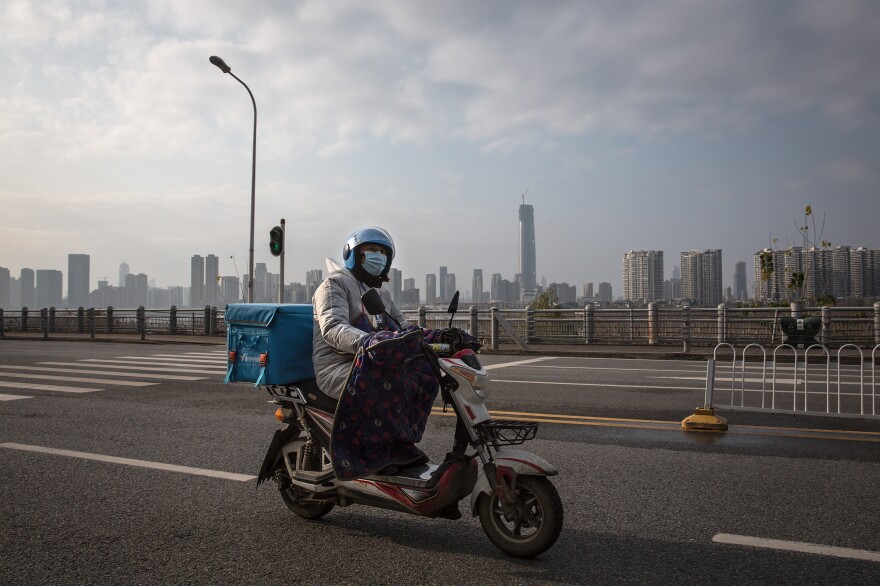 A delivery worker on a motorcycle on an empty street in Wuhan. Despite the city's lockdown measures to prevent the spread of disease, a handful of delivery companies are still in operation. Their workers provide supplies and necessities to residents cooped up in their homes.