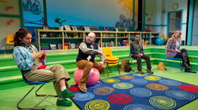 Four performers on a stage set designed to look like an elementary school library.