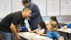 A teacher at IDEA Carver Academy in San Antonio leans down to speak to an elementary student in 2019.